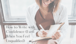 Smiling woman writing in a notebook while sitting by a window, symbolizing confidence in writing and encouragement for writers who feel unqualified.