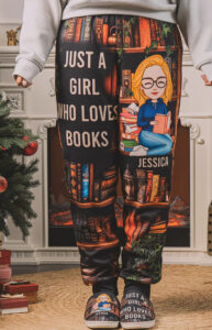 A person wearing black pajama pants and matching slippers with a design that says “Just a Girl Who Loves Books” and an illustrated girl reading. The name “Jessica” is personalized on both items.