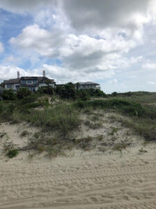 Sand dunes and beach houses on Tybee Island near Savannah, Georgia, under a partly cloudy sky on a late summer afternoon.