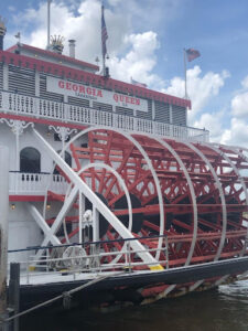 View of the Savannah River in Savannah, Georgia, featuring the Talmadge Memorial Bridge and cargo ships along the historic riverfront on a sunny day.