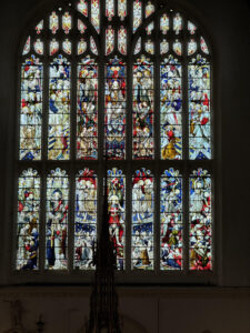 Large, detailed stained glass church window depicting biblical scenes with vibrant colors and intricate figures.